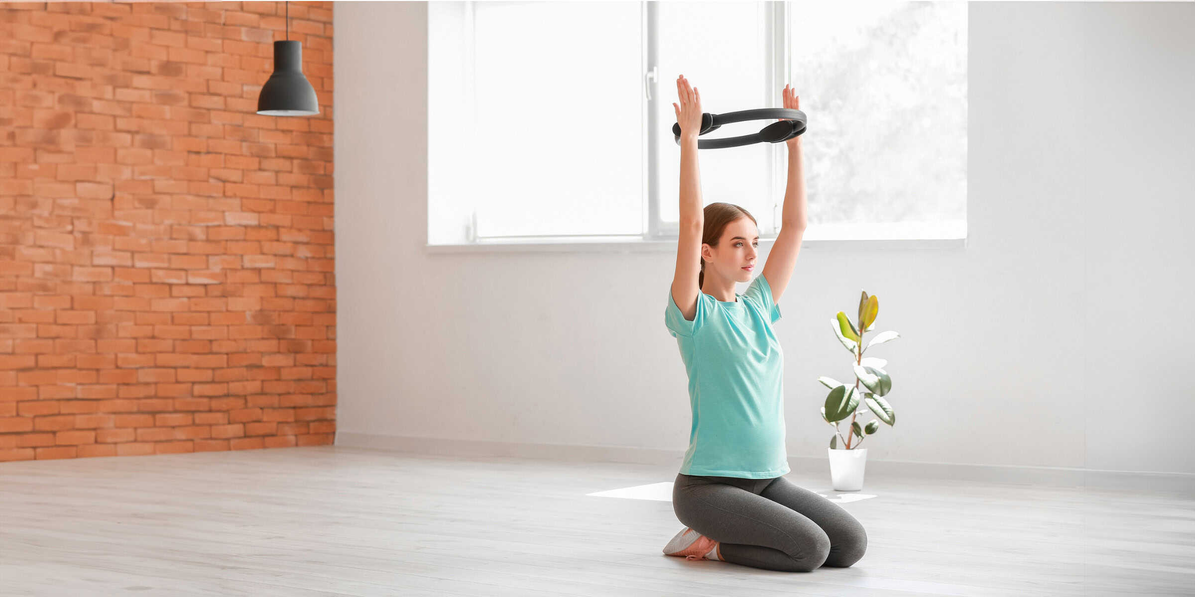 A woman doing yoga in a room with a brick wall.
