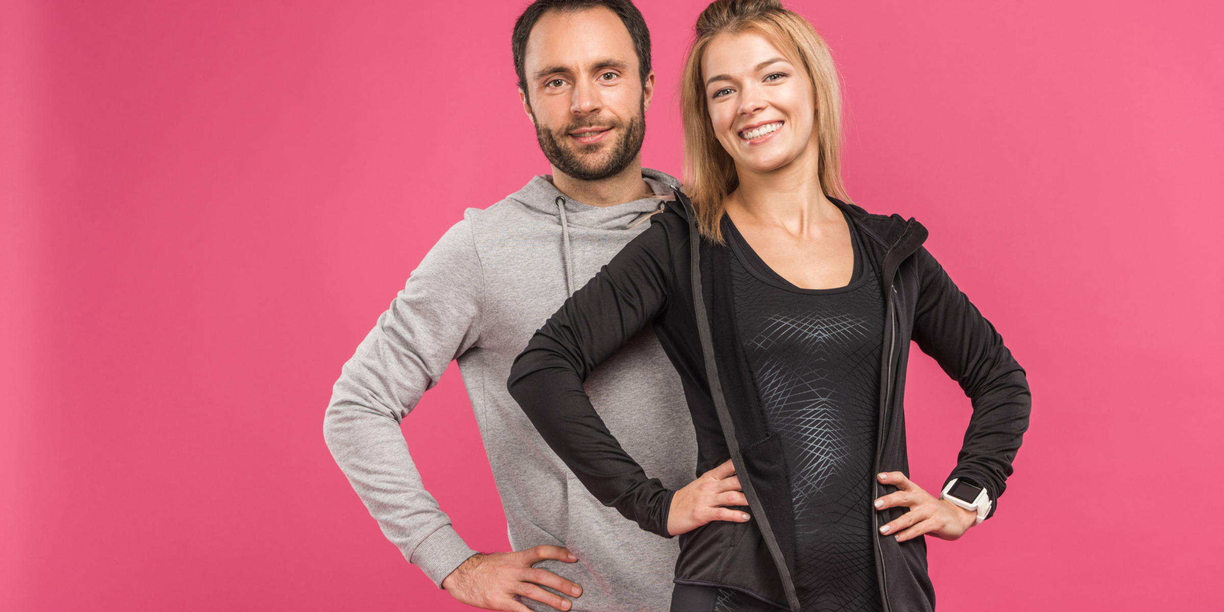 A couple posing on a pink background.