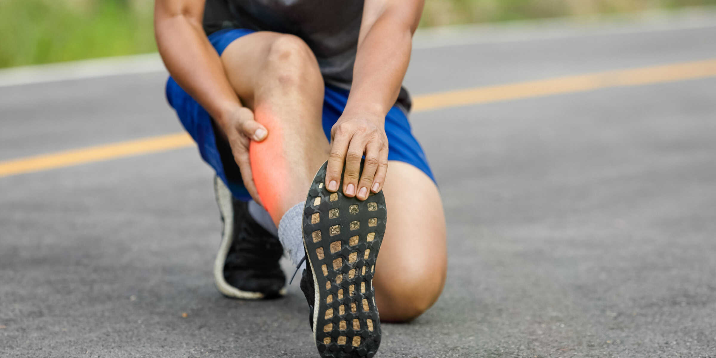 A man with a pain in his foot is sitting on the road.