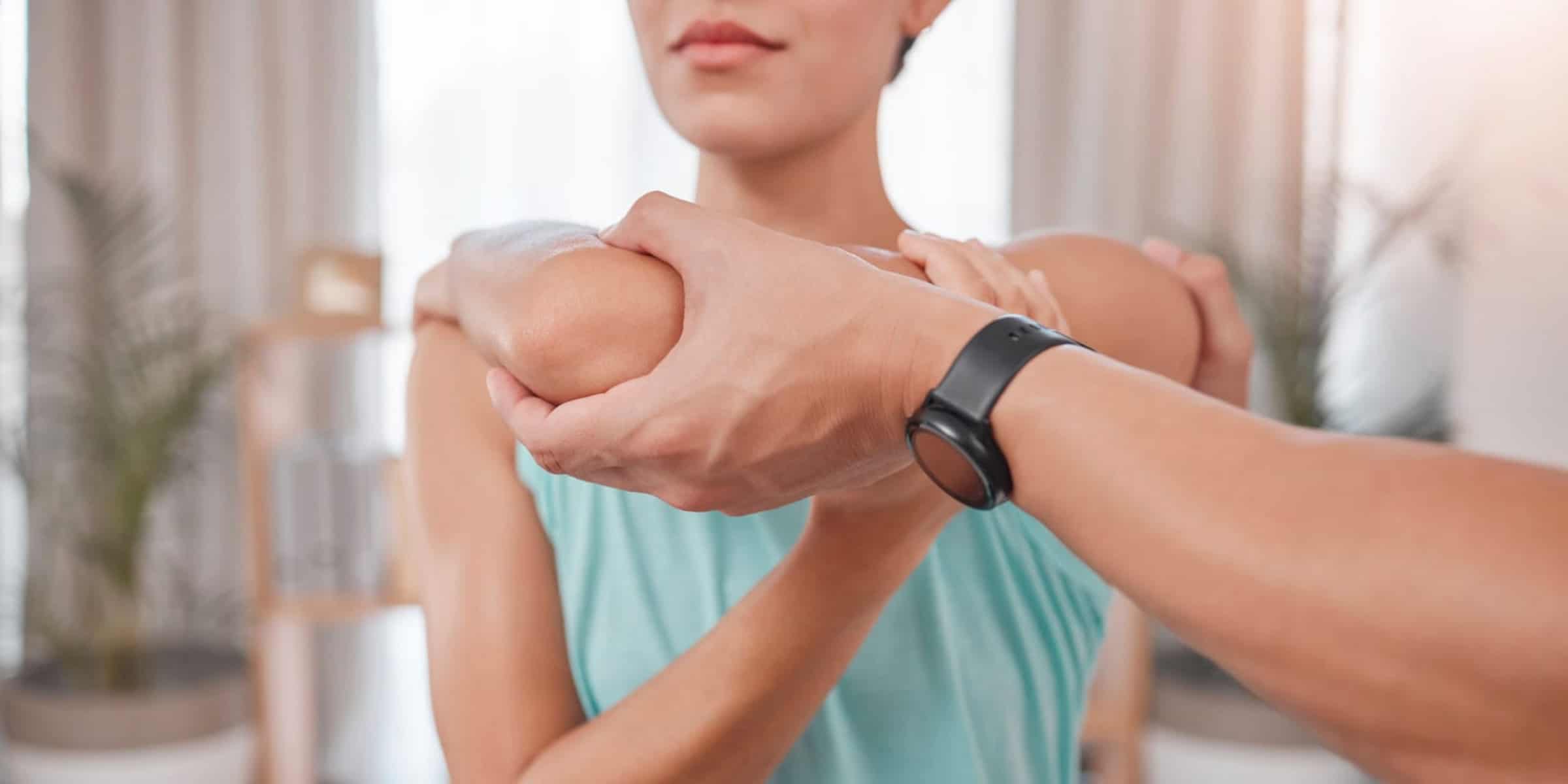 A woman is getting her arm massaged by a physical therapist.