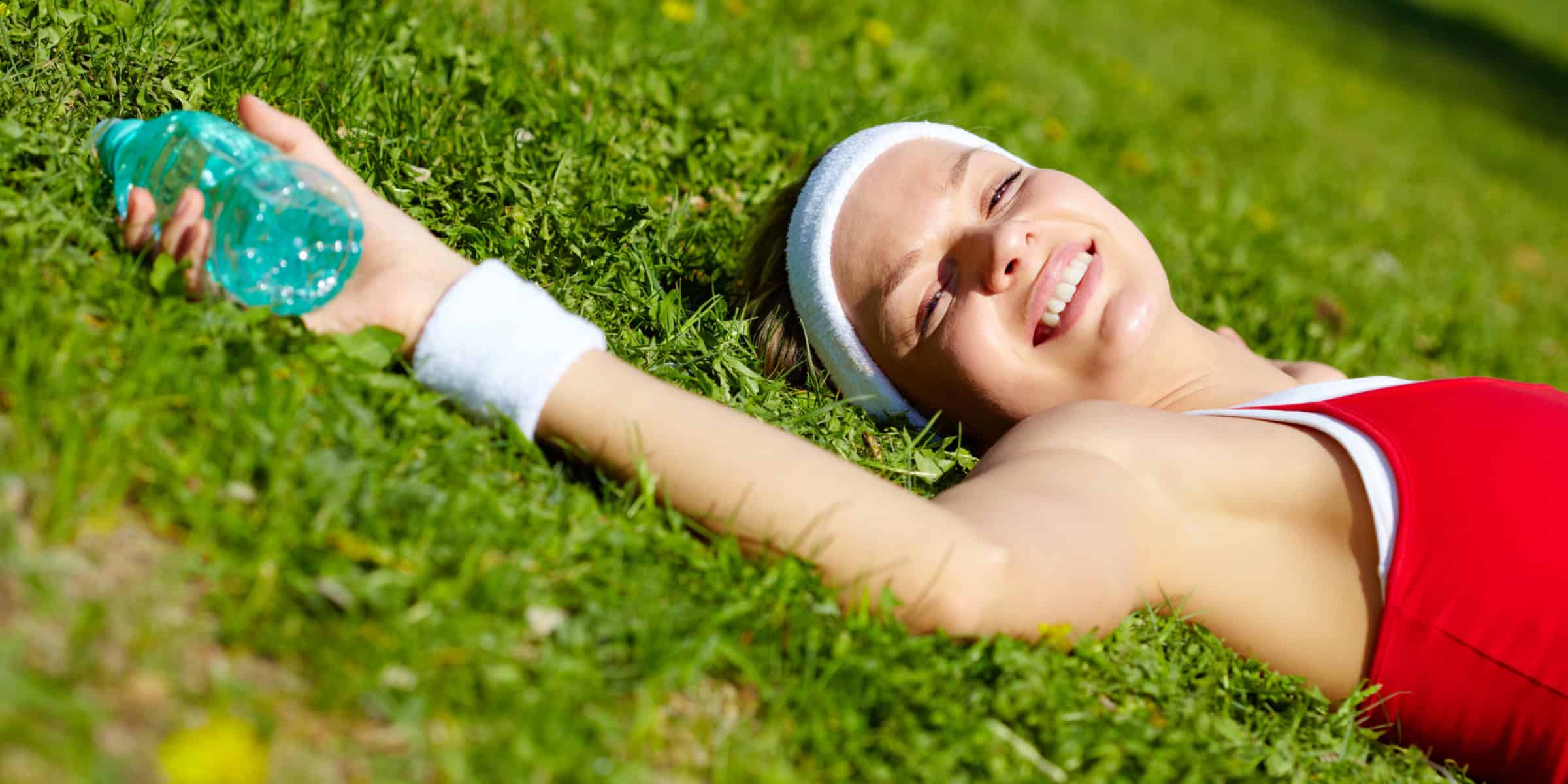 A woman laying in the grass with a bottle.