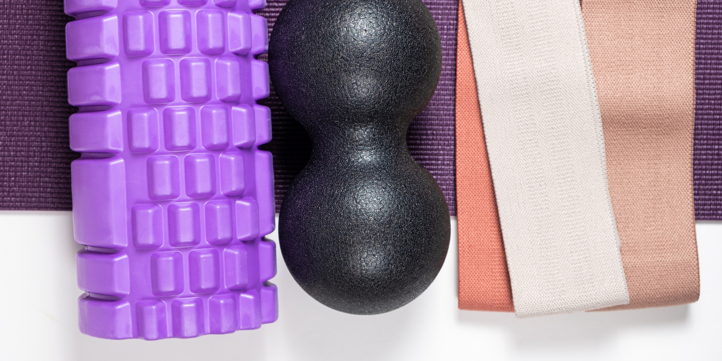 A purple yoga mat, a purple foam roller, and a purple foam roller.