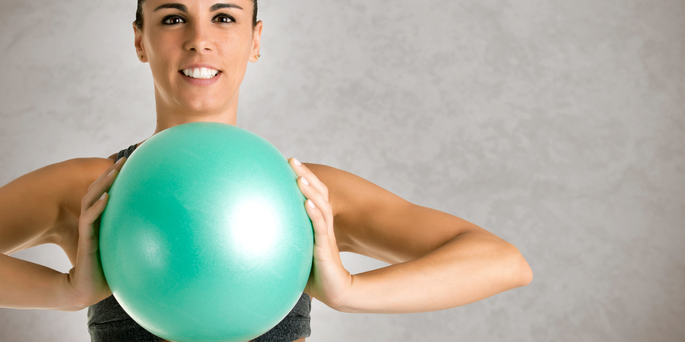 A woman holding a green exercise ball.