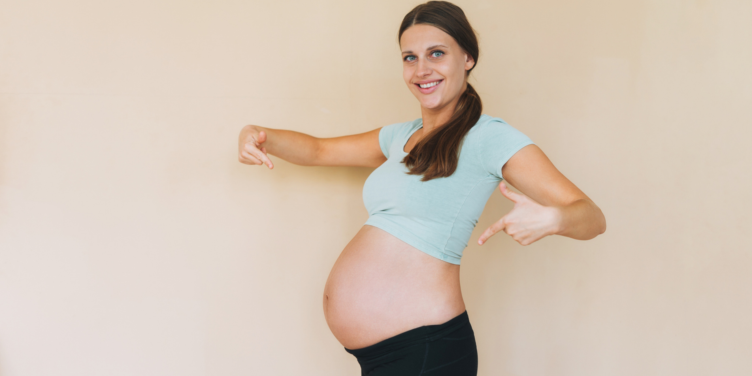 A pregnant woman is pointing her finger at the camera.
