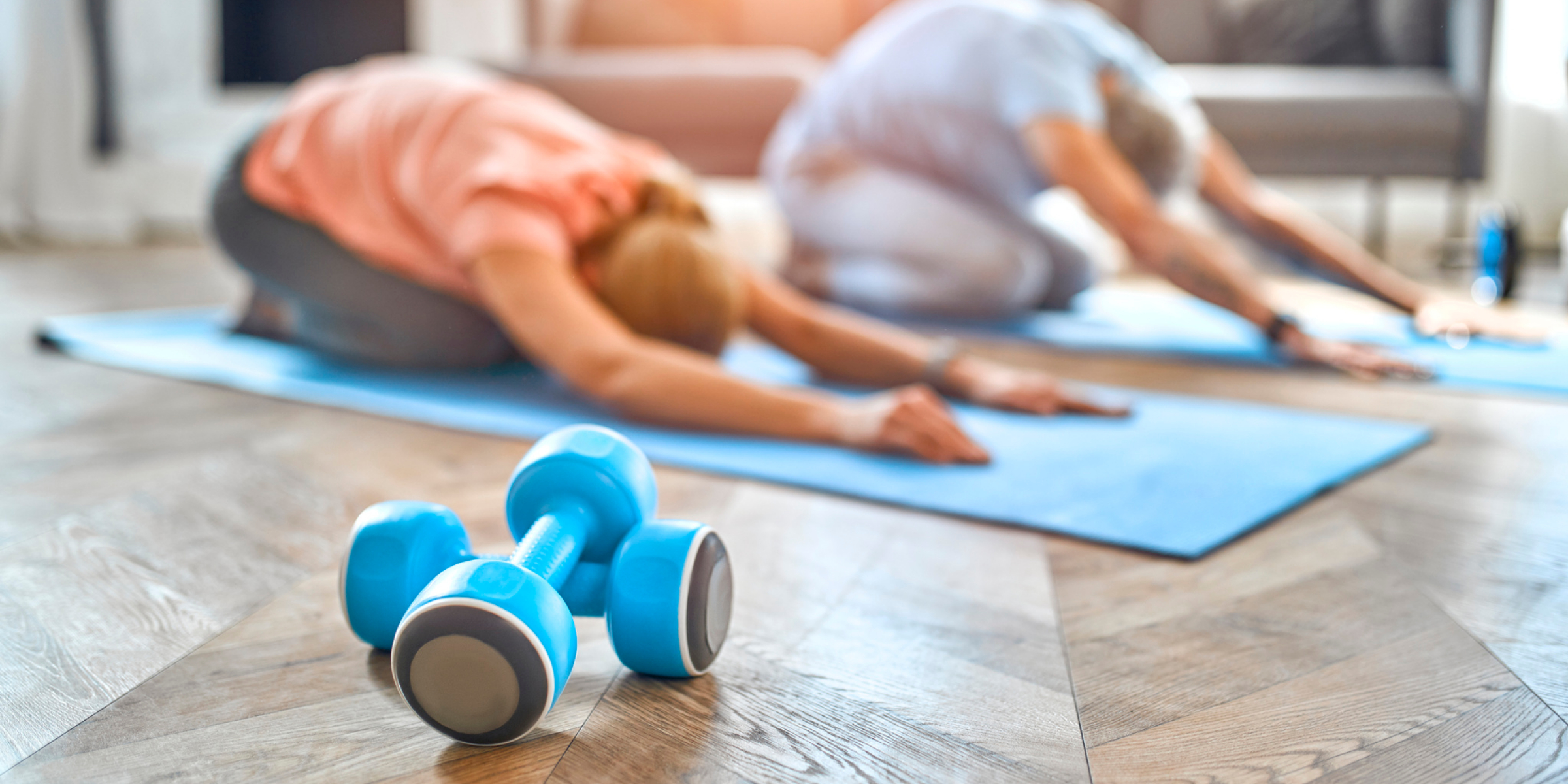 Two people doing yoga with dumbbells in the living room.