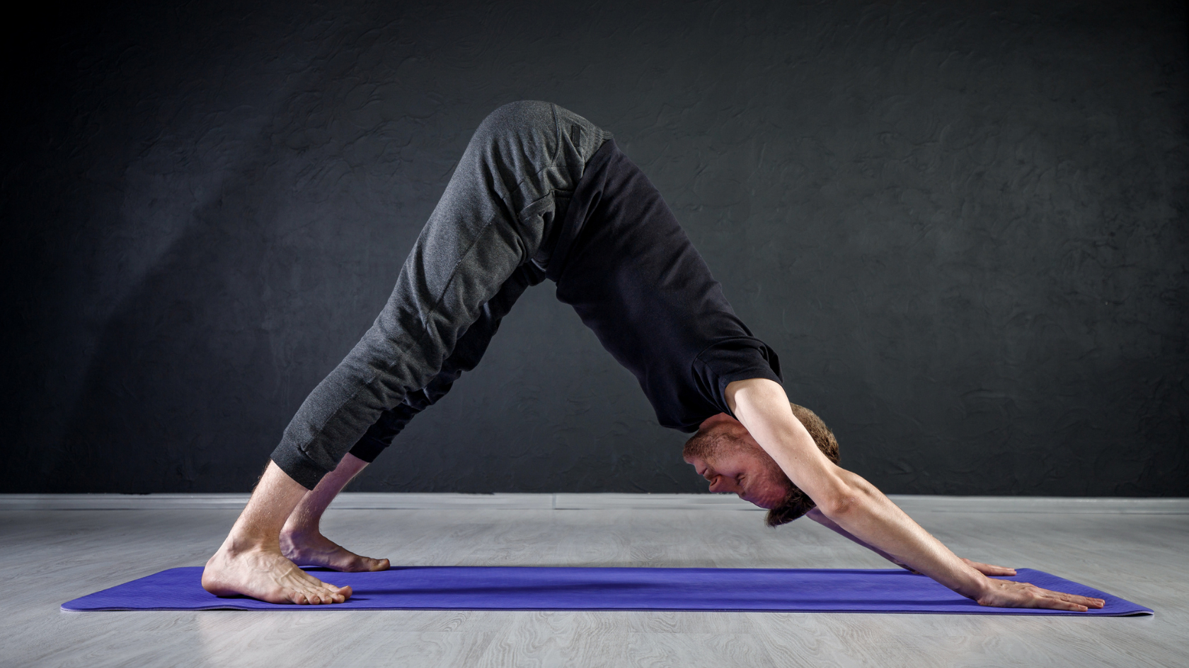 A man doing a yoga pose on a blue mat.